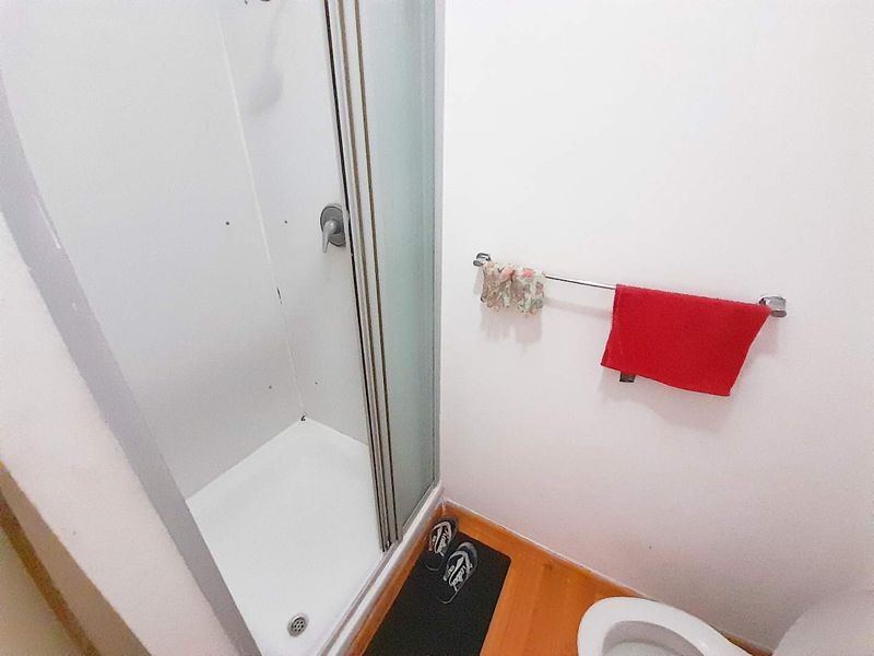 A compact bathroom featuring a shower enclosure and a standard toilet with a wall-mounted towel rail.