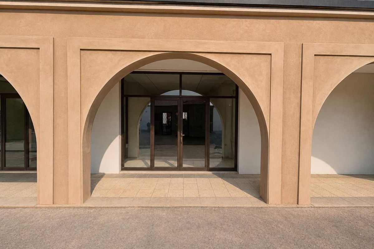 A clean, modern retail storefront entrance featuring elegant arched masonry detailing and glass double doors.