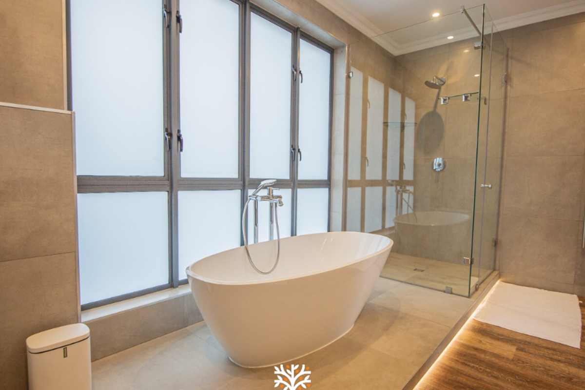 Modern bathroom featuring a freestanding bathtub, a glass-enclosed walk-in shower, and large frosted windows with contemporary tile finishes and integrated floor lighting.