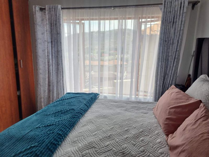 A cozy bedroom featuring a built-in wardrobe and a large window that allows for natural light and scenic views.