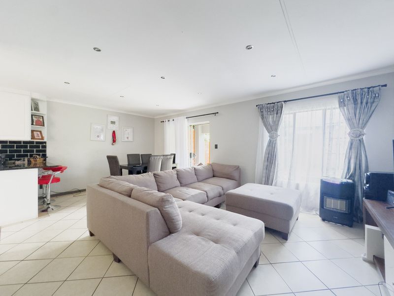 Spacious open-plan living and dining area featuring tiled flooring, recessed lighting, and a modern kitchen with a subway tile backsplash.