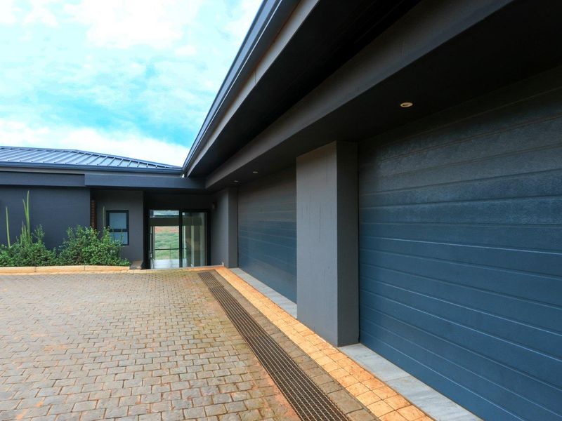 Modern exterior view featuring a paved driveway, double garage doors, and contemporary dark-toned architectural finishes.