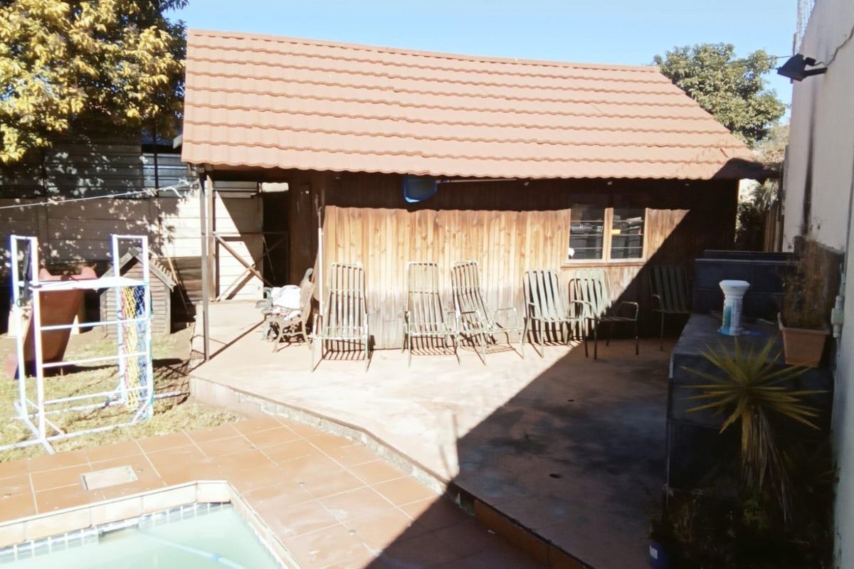 Outdoor entertainment area featuring a timber-clad structure, paved patio space, and adjacent swimming pool.