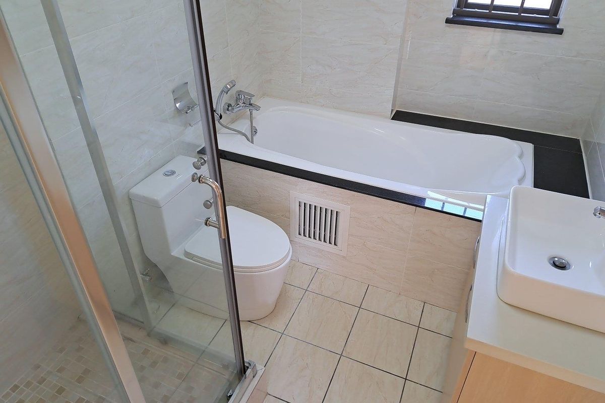 A clean, modern bathroom featuring a separate bathtub, glass-enclosed shower, vessel sink vanity, and neutral wall and floor tiling.