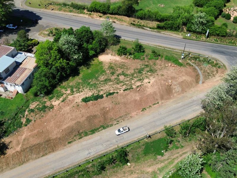 An aerial view of a vacant commercial land plot situated at a road intersection, offering potential for development.