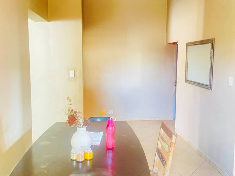A dining area featuring tiled flooring and neutral wall tones, offering a functional space ready for potential cosmetic updates.