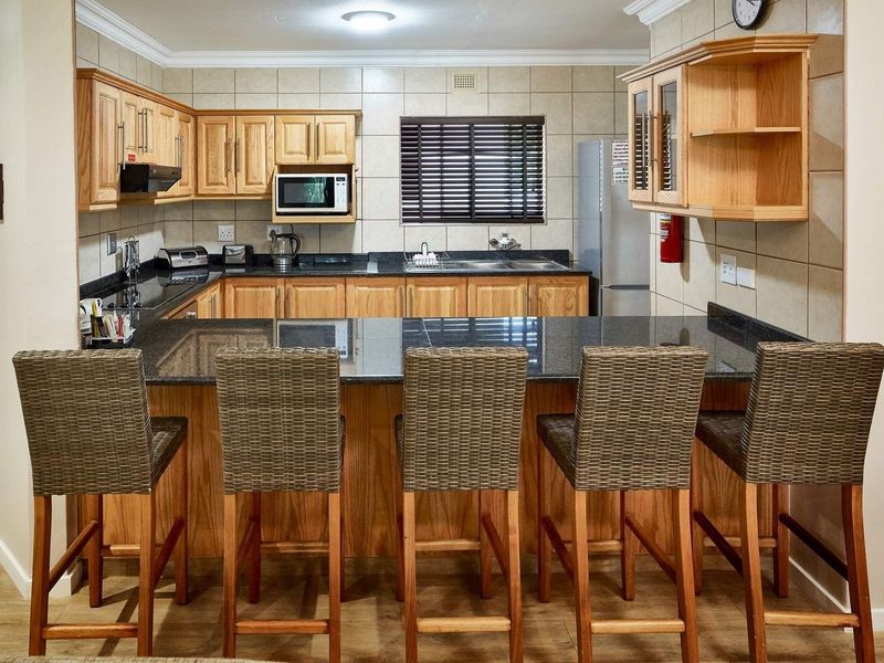A functional kitchen featuring wooden cabinetry, granite countertops, a breakfast bar, and a tiled backsplash, providing a practical and well-organized cooking space.