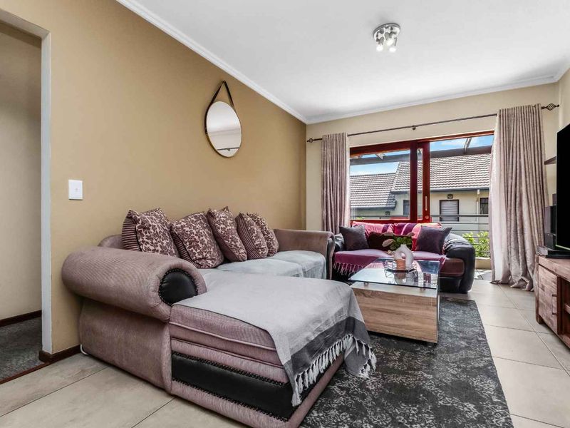A comfortable living room featuring tiled flooring, neutral wall tones, and a sliding glass door providing access to an outdoor balcony area.