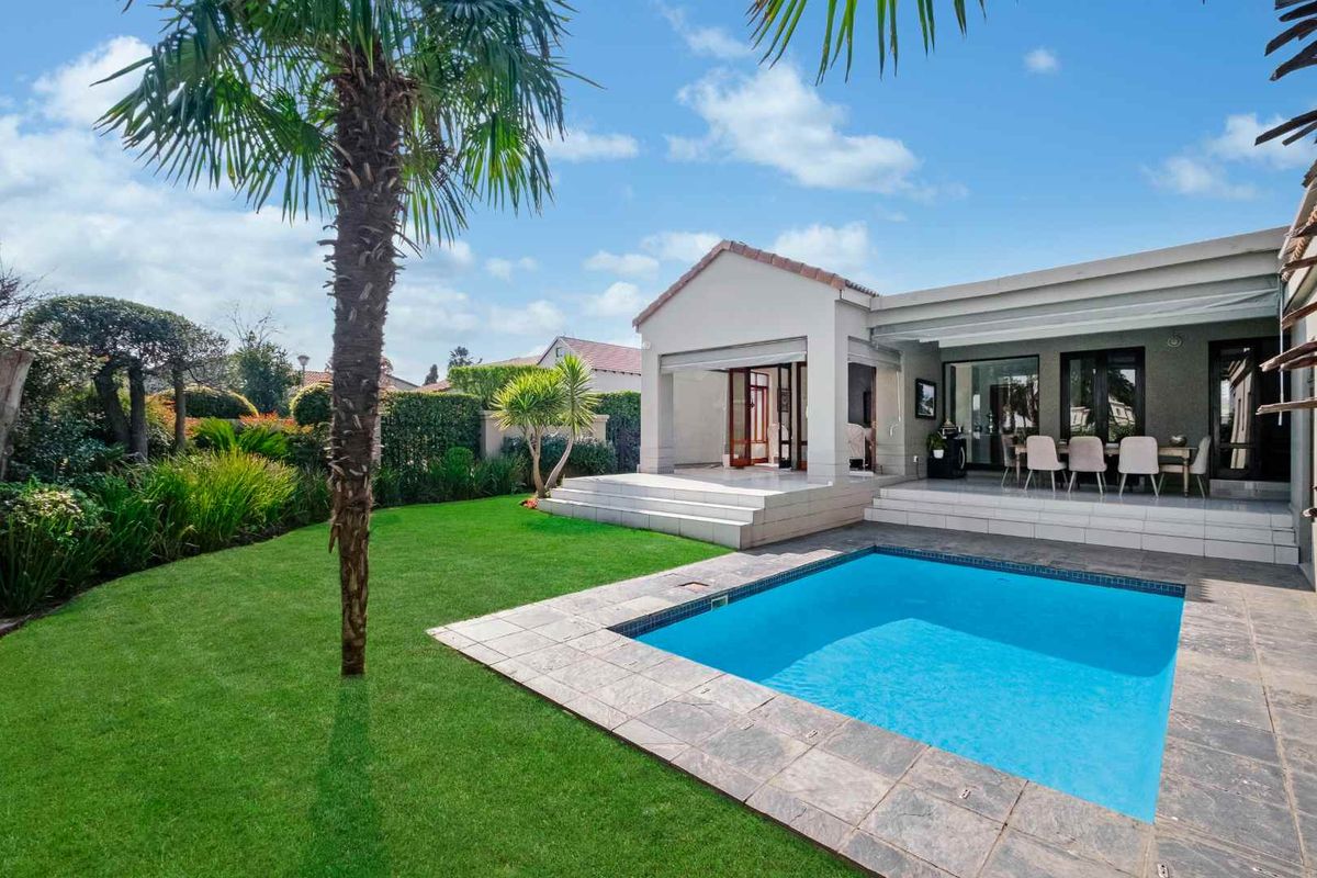 A well-maintained rear exterior featuring a swimming pool, tiled patio area, and a lush landscaped garden.