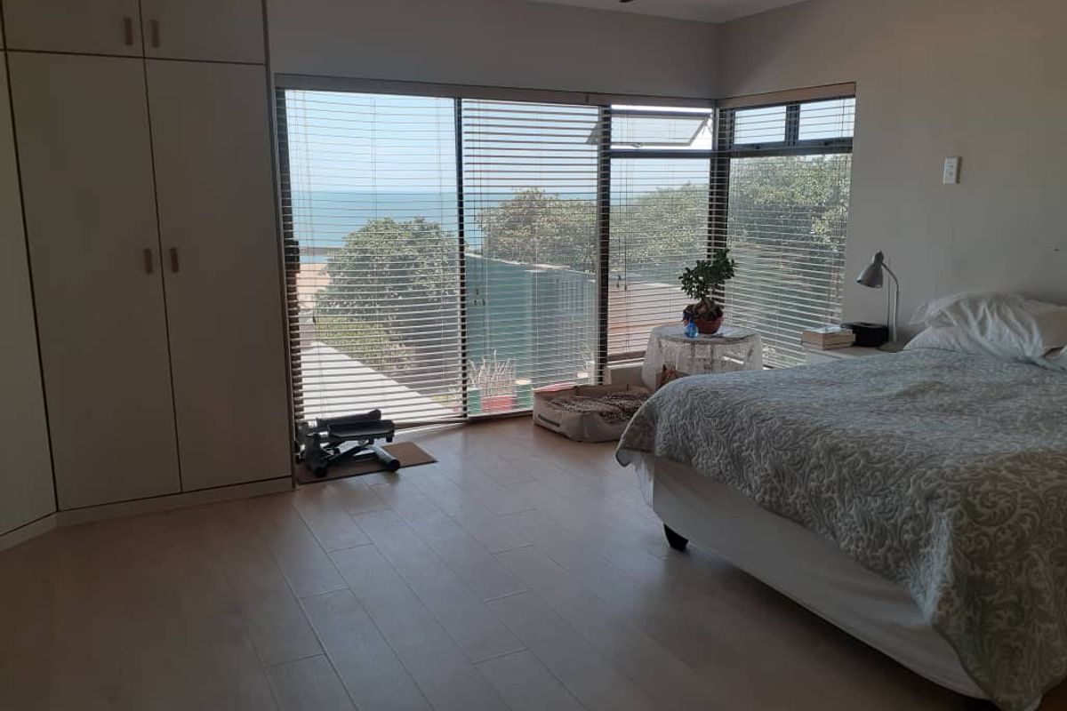 Spacious bedroom featuring large windows with ocean views, built-in cabinetry, and light-toned flooring.