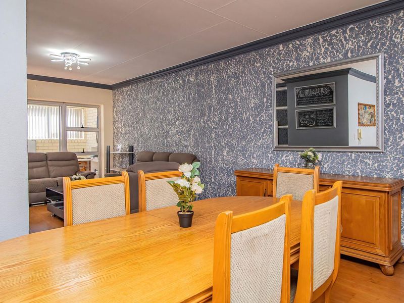 Open plan dining and living area featuring laminate flooring, textured feature wall, and crown molding, providing a functional space for entertaining.