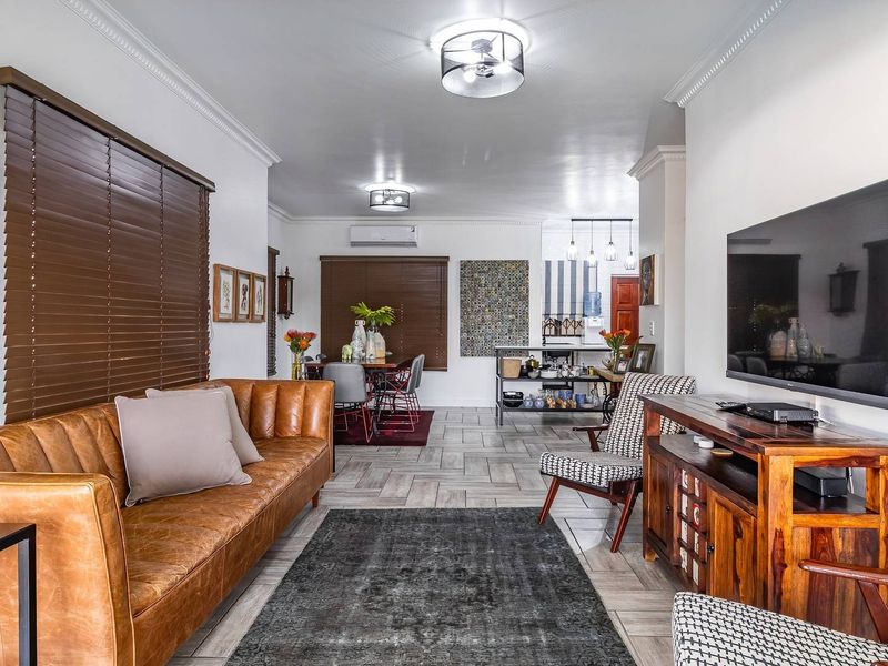 Spacious open-plan living and dining area featuring tiled flooring, crown molding, and modern split-system air conditioning, creating a bright and functional living space.