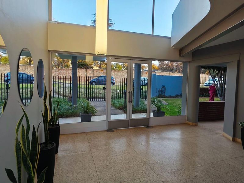 Spacious entrance foyer featuring high ceilings, expansive glass windows providing natural light, and durable terrazzo flooring.