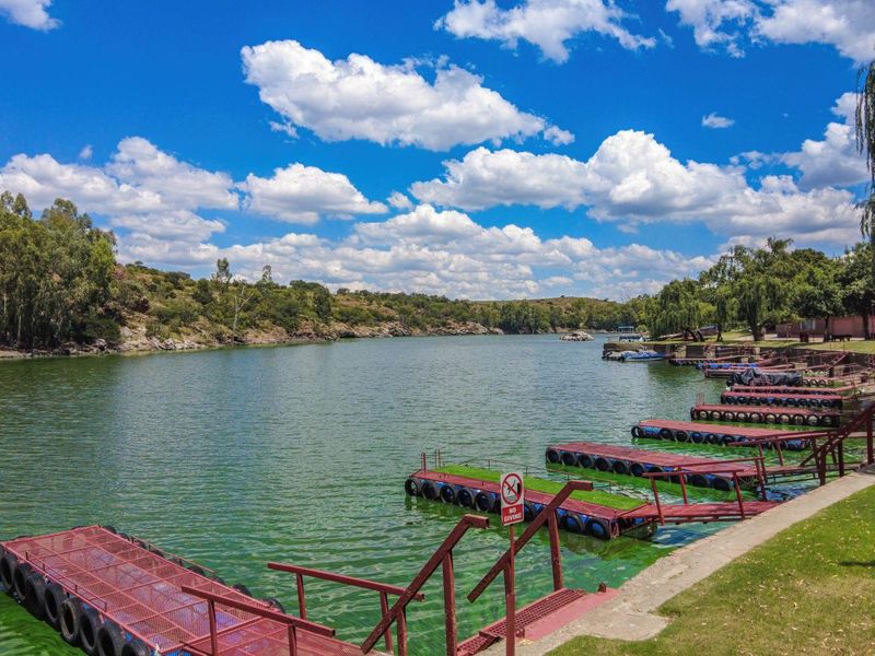 Scenic view of a lake featuring multiple floating jetties with metal railings and well-maintained grassy banks.