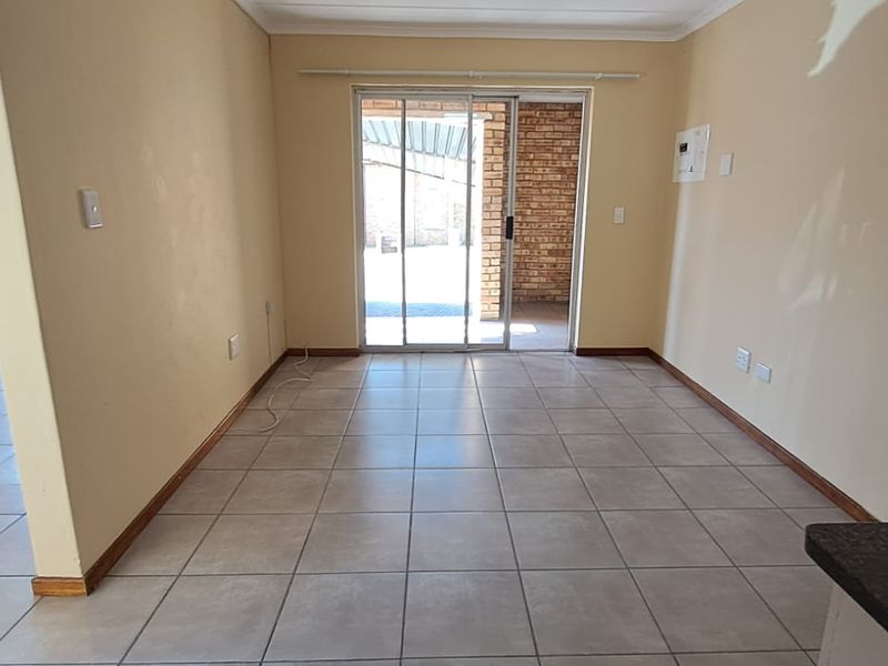 An empty, tiled living area featuring a sliding glass door that provides access to an outdoor patio space.