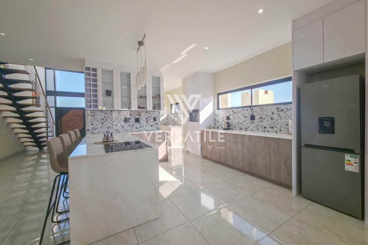 Modern kitchen featuring a central island with stone countertops, sleek cabinetry, and high-quality tiled flooring, seamlessly integrated into an open-plan living space.