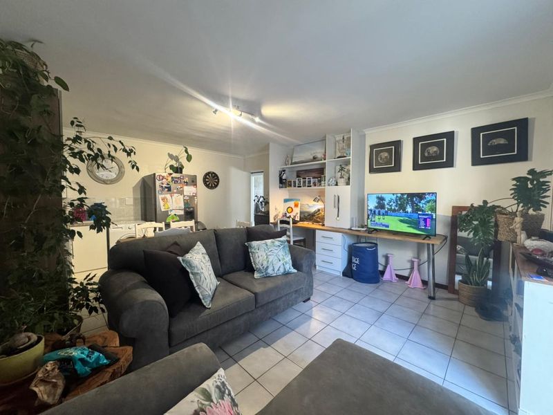 Open-plan living area featuring tiled flooring, built-in desk space, and integrated shelving, creating a functional and versatile living environment.