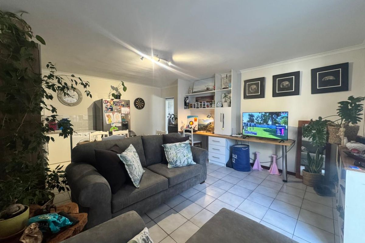 Open-plan living area featuring tiled flooring, built-in desk space, and integrated shelving, creating a functional and versatile living environment.