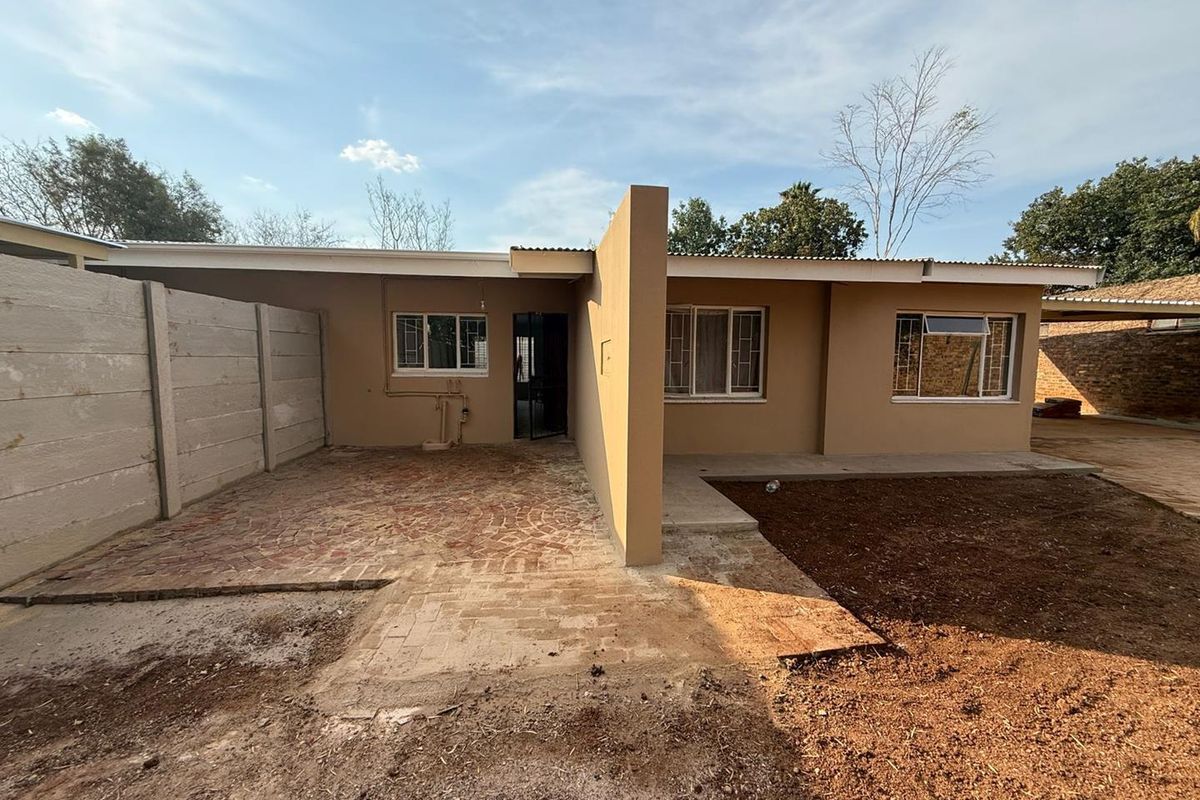 Rear exterior view of the house featuring a brick paved patio area, precast boundary wall, and security-fitted windows.