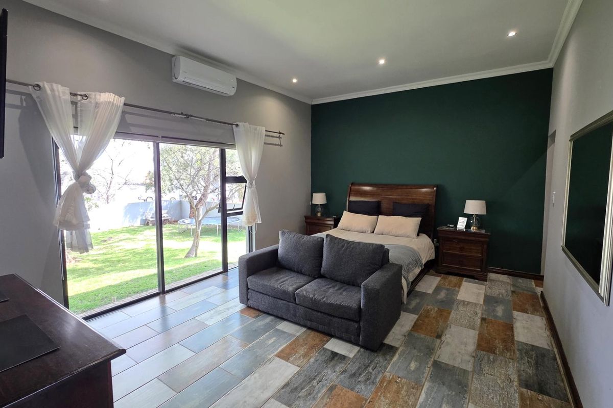 Spacious bedroom featuring modern tiled flooring, a split-system air conditioner, and large sliding glass doors providing direct access to the garden.