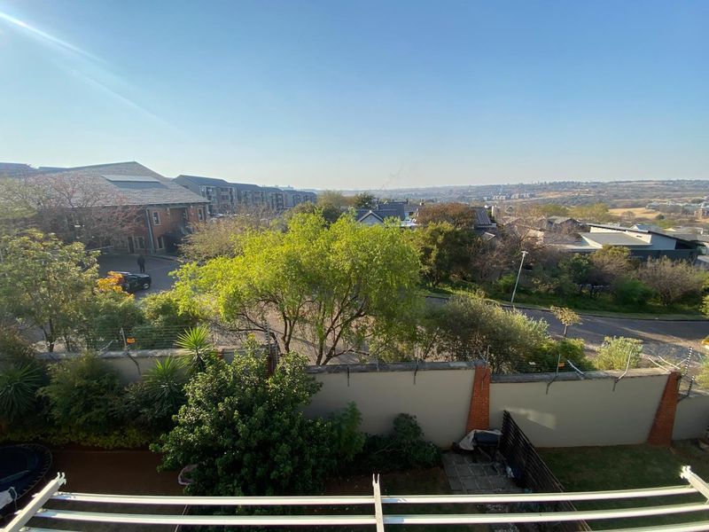 An elevated view overlooking the surrounding residential neighborhood, featuring a perimeter wall with electric fencing and mature trees.