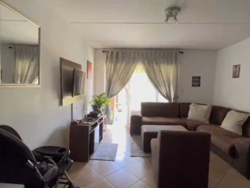 A living room featuring tiled flooring and a sliding glass door providing natural light and access to the outdoor area.