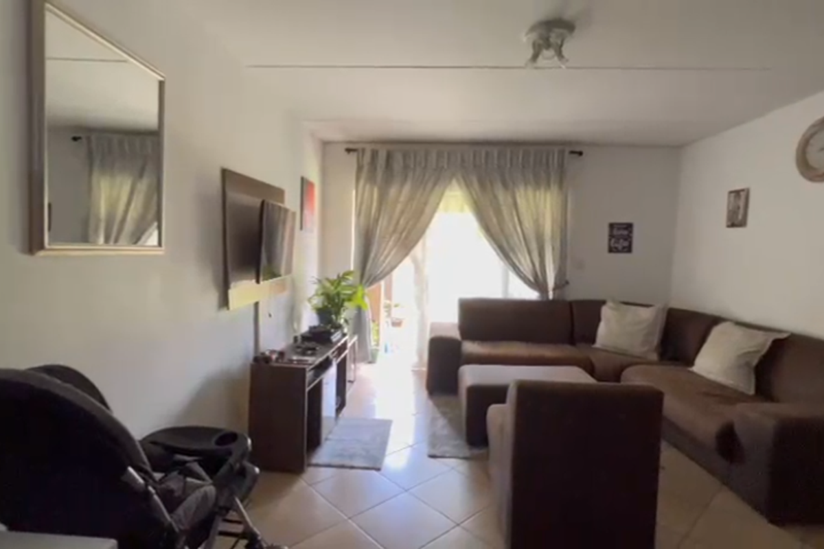 A living room featuring tiled flooring and a sliding glass door providing natural light and access to the outdoor area.