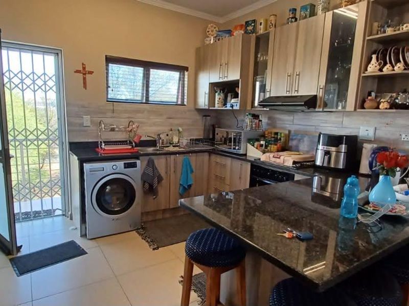 Functional kitchen featuring granite countertops, built-in cabinetry, a breakfast nook, and direct access to an exterior security gate.
