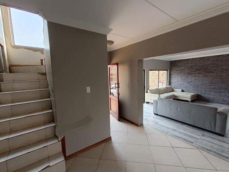 Entrance foyer featuring tiled staircase and open-plan access to the living area with a stone-cladding feature wall.