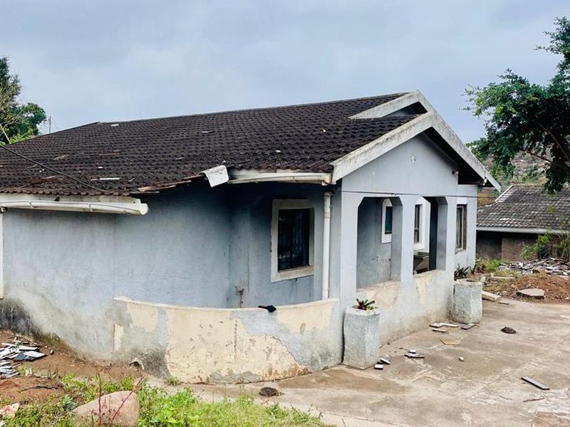 Exterior view of a single-story house showing significant wear to the roof tiles and exterior wall plaster, requiring maintenance and renovation.