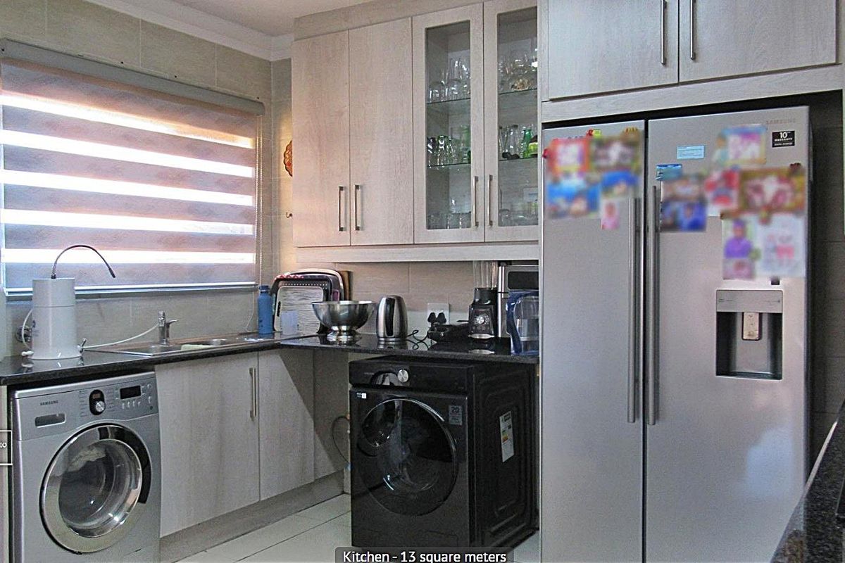 A functional kitchen featuring light wood-finish cabinetry, granite countertops, tiled backsplash, and integrated space for laundry appliances.