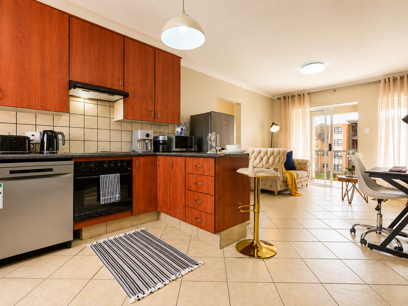 Open-plan kitchen and living area featuring cherry wood cabinetry, tiled flooring, and a sliding door leading to a balcony.