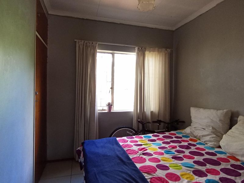 A bedroom featuring tiled flooring and a built-in wardrobe, requiring cosmetic updates to the ceiling and wall finishes.