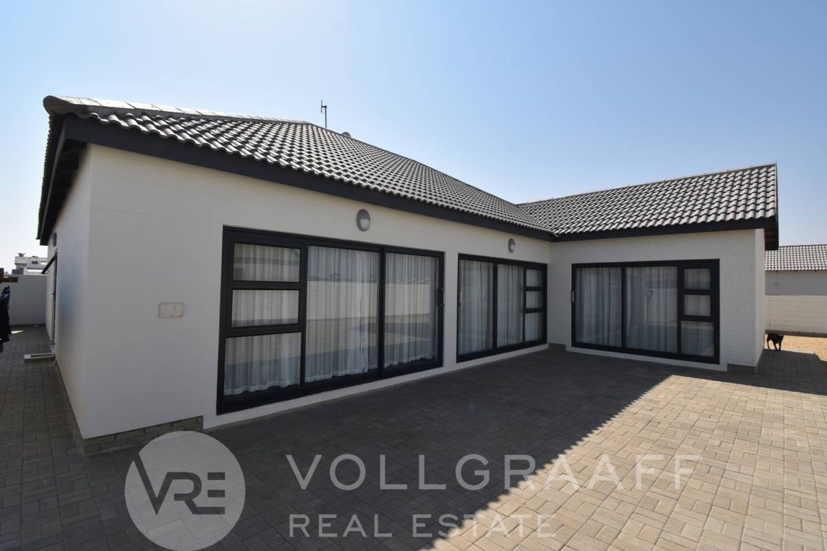 Rear exterior view of the property featuring a paved patio area and large sliding glass doors leading into the home.