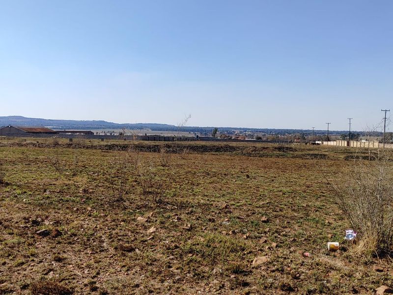 A wide-angle view of the vacant agricultural land, showcasing the open terrain, surrounding perimeter fencing, and distant landscape horizon.