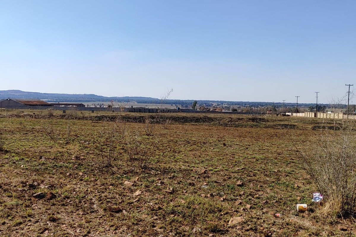 A wide-angle view of the vacant agricultural land, showcasing the open terrain, surrounding perimeter fencing, and distant landscape horizon.