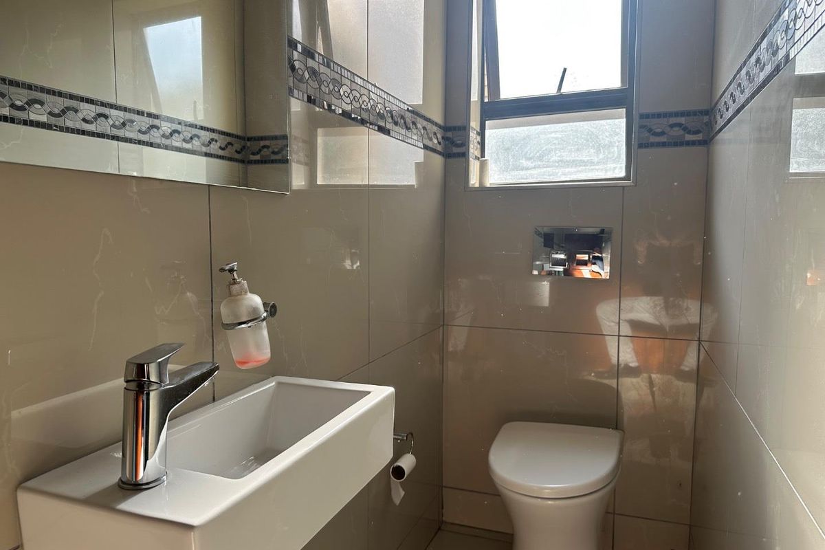 A compact, modern guest bathroom featuring floor-to-ceiling wall tiles, a wall-mounted basin, and a concealed cistern toilet.