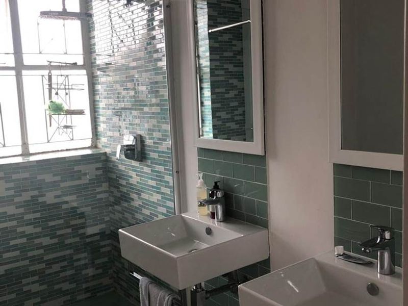 Modern bathroom featuring a walk-in shower, dual wall-mounted washbasins, and stylish mosaic and subway tile finishes.