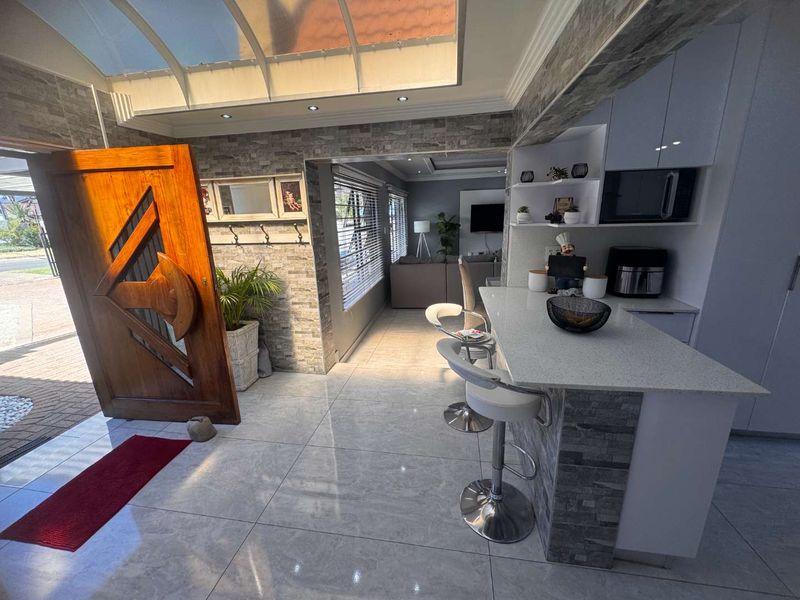 Modern open-plan living area featuring stone veneer accents, a bright translucent roof section, and a sleek kitchen island with quartz countertops.