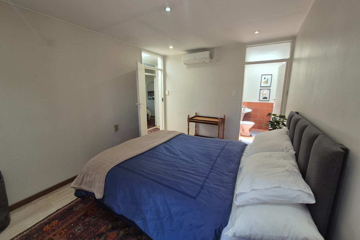 A bedroom featuring laminate flooring, recessed lighting, an air conditioning unit, and direct access to an en-suite bathroom.