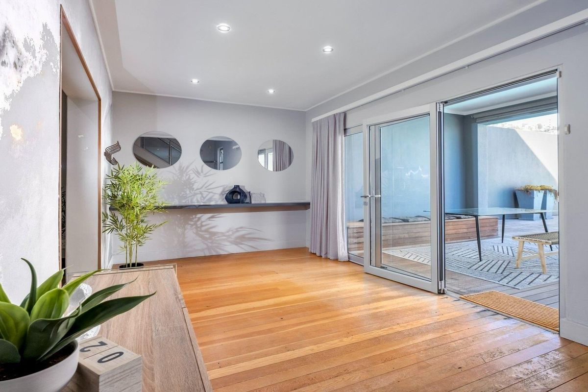 Bright and spacious living area featuring polished hardwood flooring, recessed lighting, and seamless access to an outdoor patio through large sliding glass doors.