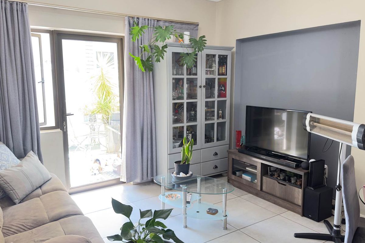 A comfortable living room featuring tiled flooring, a recessed feature wall, and a glass door providing direct access to an outdoor patio area.