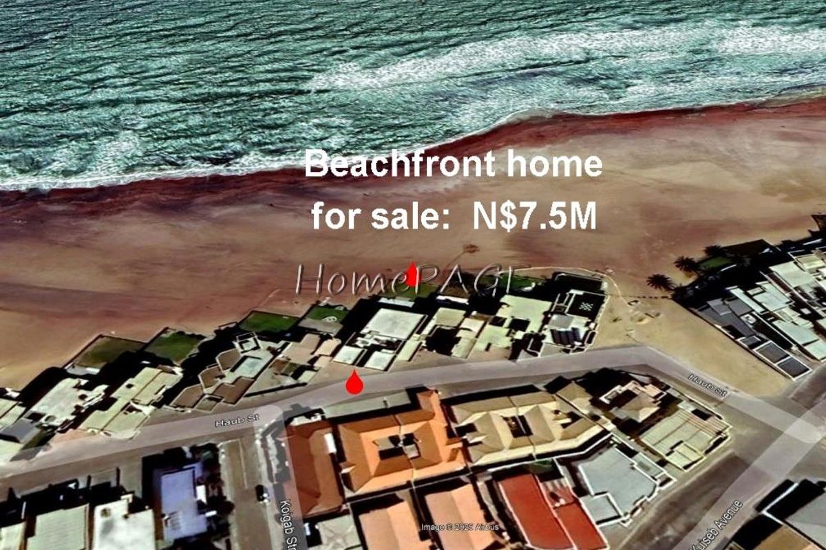 Aerial view of a coastal residential property located along the beachfront, showing the surrounding neighborhood layout and proximity to the ocean.