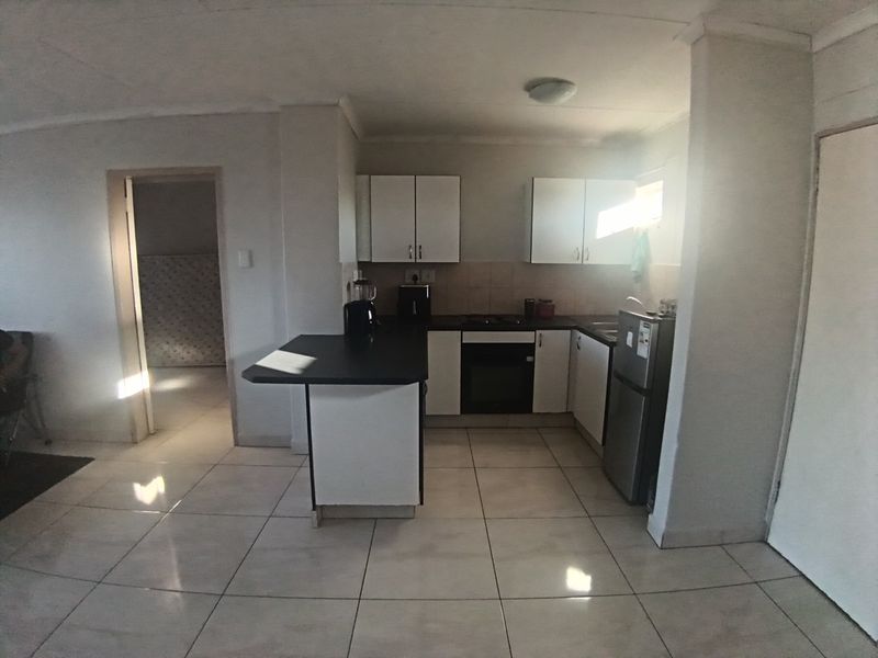 A functional kitchen featuring white cabinetry, dark laminate countertops, a built-in oven, and tiled flooring with an integrated breakfast bar.