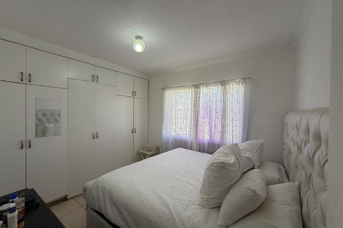 A bedroom featuring built-in floor-to-ceiling wardrobes and tiled flooring, providing ample storage space and a neutral aesthetic.