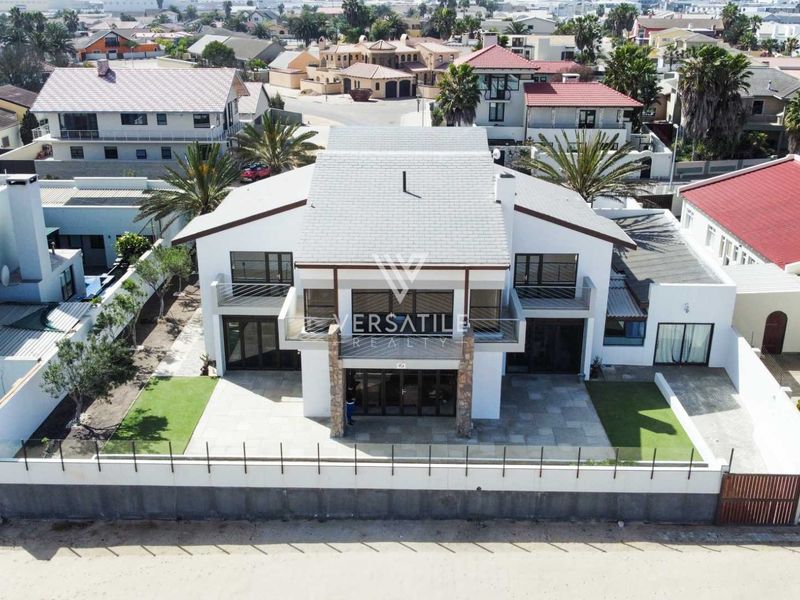 Aerial view of a modern two-story residential property featuring a tiled roof, balconies, stone accents, and a paved patio area.