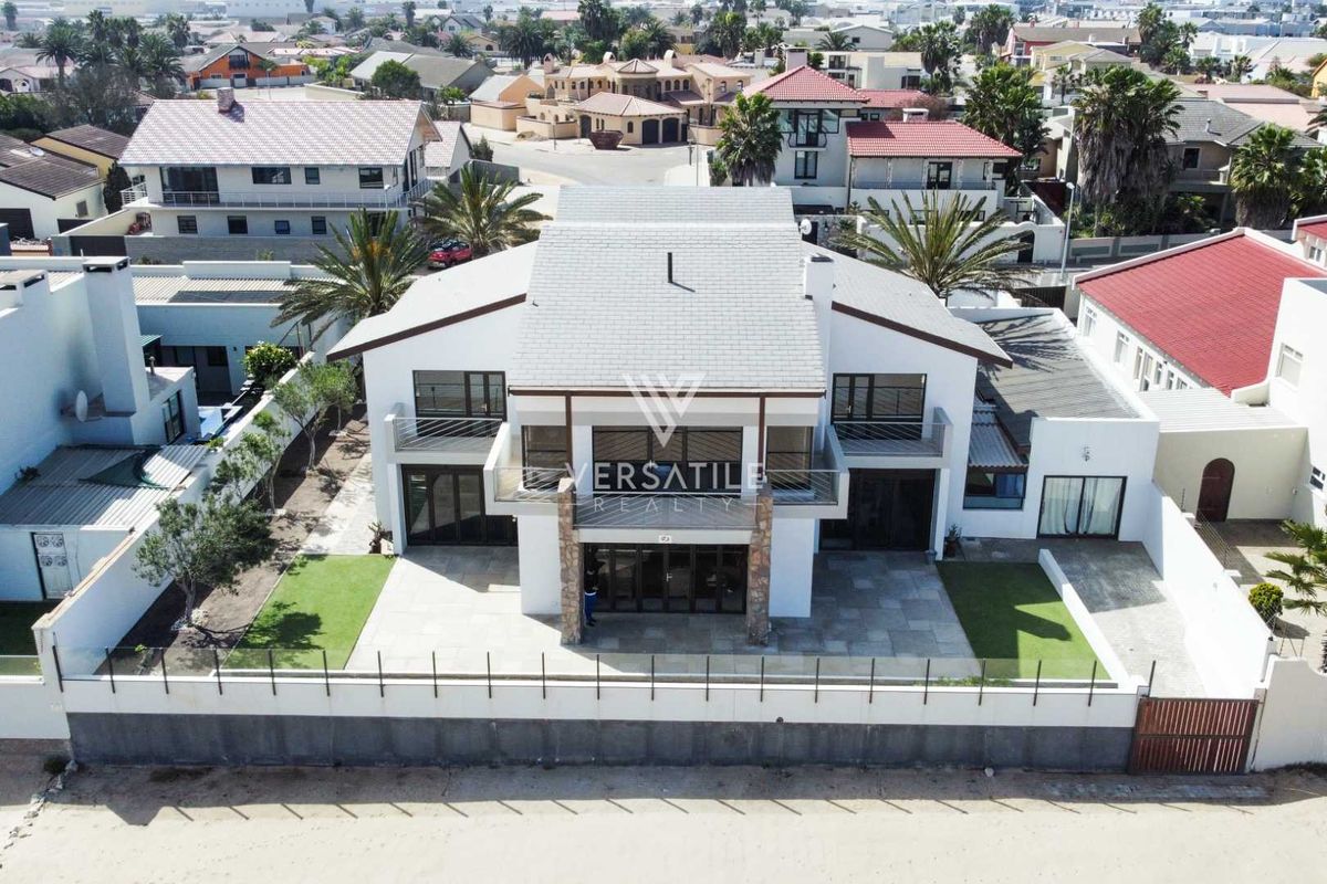 Aerial view of a modern two-story residential property featuring a tiled roof, balconies, stone accents, and a paved patio area.