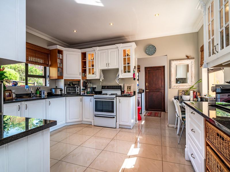 A well-maintained kitchen featuring white cabinetry, granite countertops, tiled flooring, and a freestanding oven, offering a bright and functional cooking space.