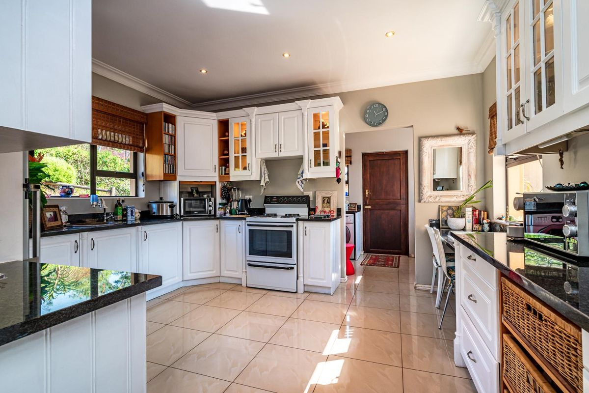 A well-maintained kitchen featuring white cabinetry, granite countertops, tiled flooring, and a freestanding oven, offering a bright and functional cooking space.