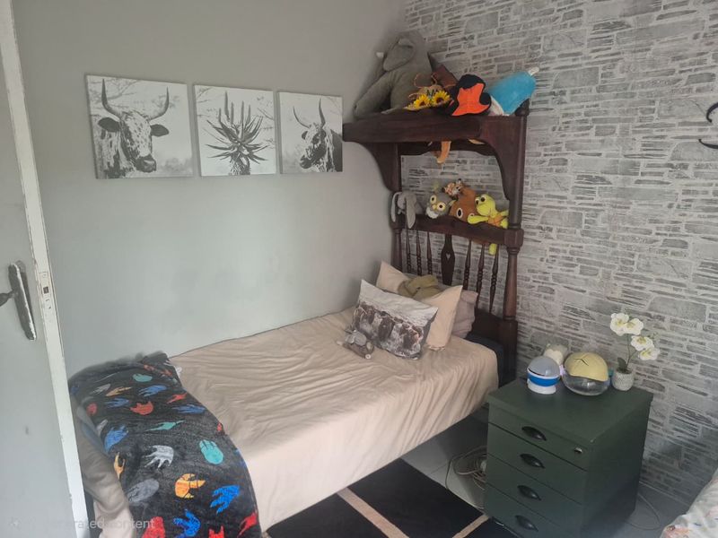 A compact bedroom featuring a textured stone-effect feature wall and neutral painted walls, providing a functional space for a single bed.